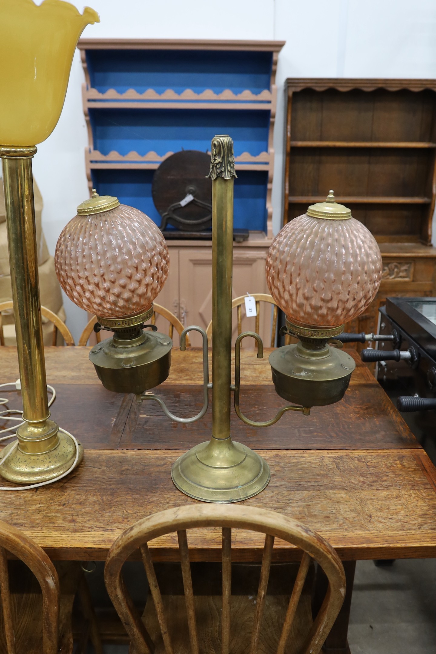 A pair of tall brass table lamps, height 65cm together with a brass two branch oil lamp with peach glass shades